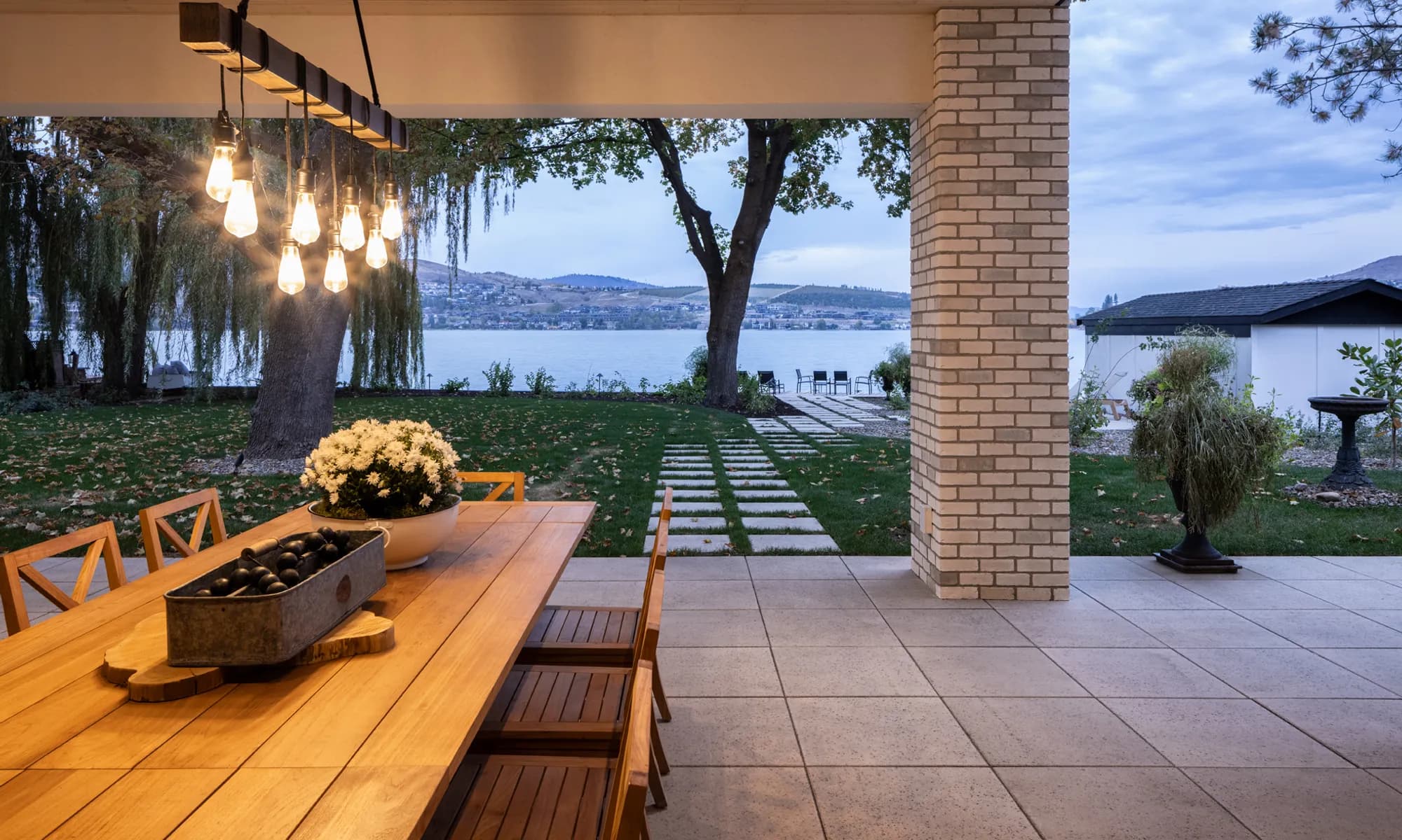lake front home with pillar and outdoor lighting