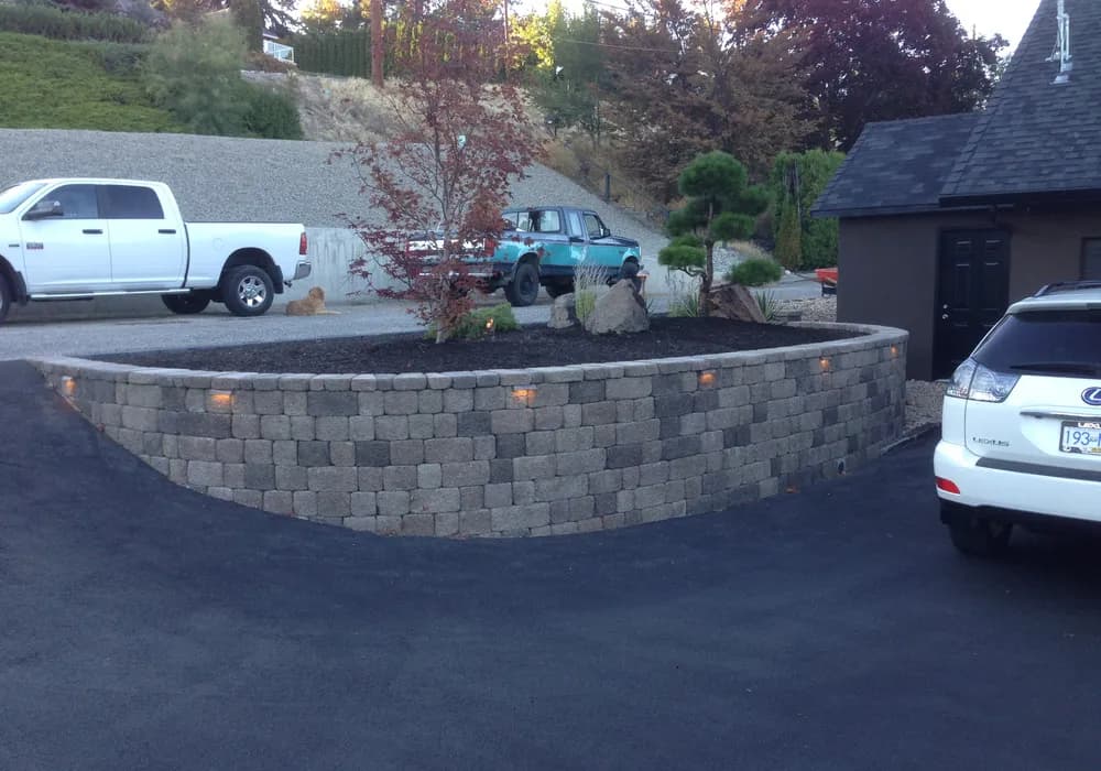 retaining wall with tree and two trucks in the background