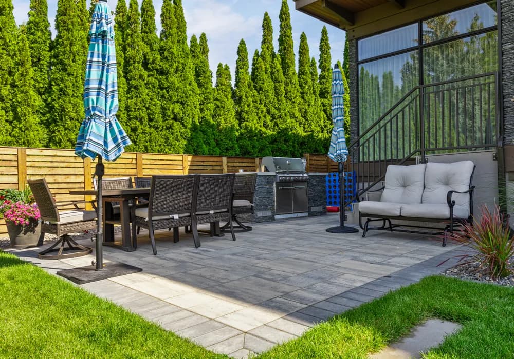 stone patio and bbq and green hedges
