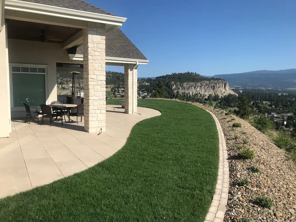 Landscape edging with a green lawn and a view of kelowna from a mountain top