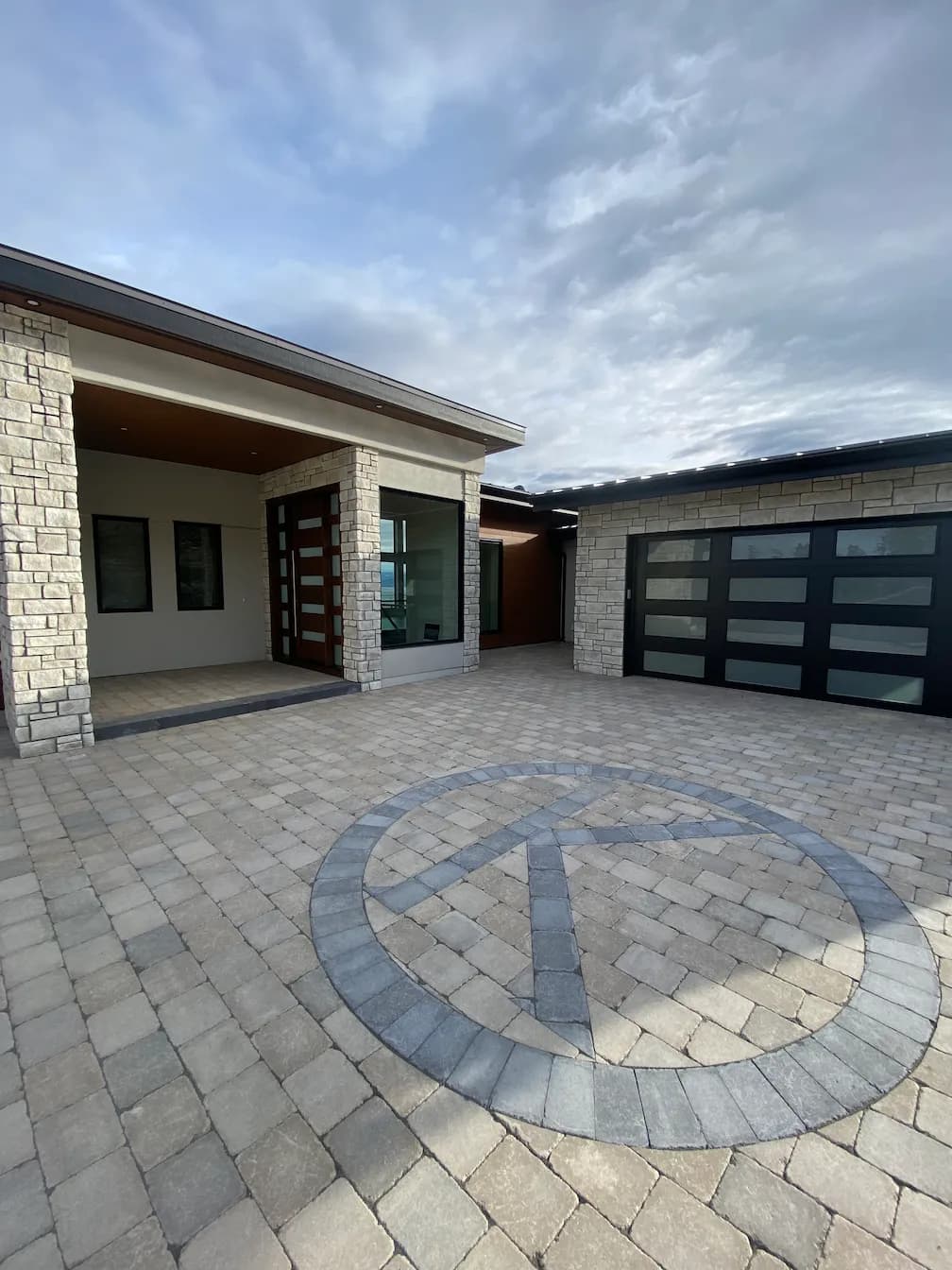 Home with a large paver driveway with a k circled in the middle with paver stones